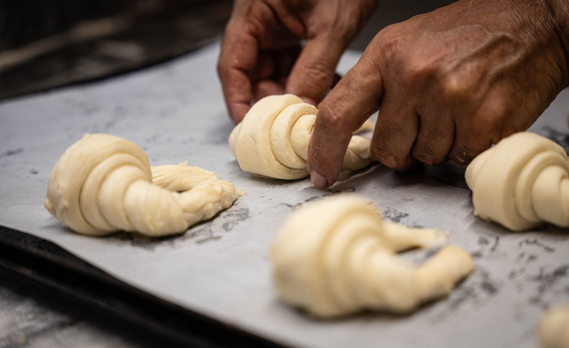 Mans fent croissants a l’obrador de L’Exquisit Forn